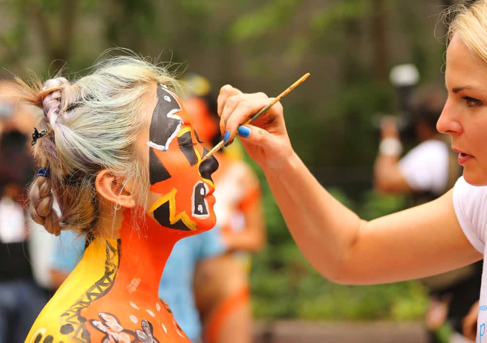 A makeup artist doing body paint for a model.