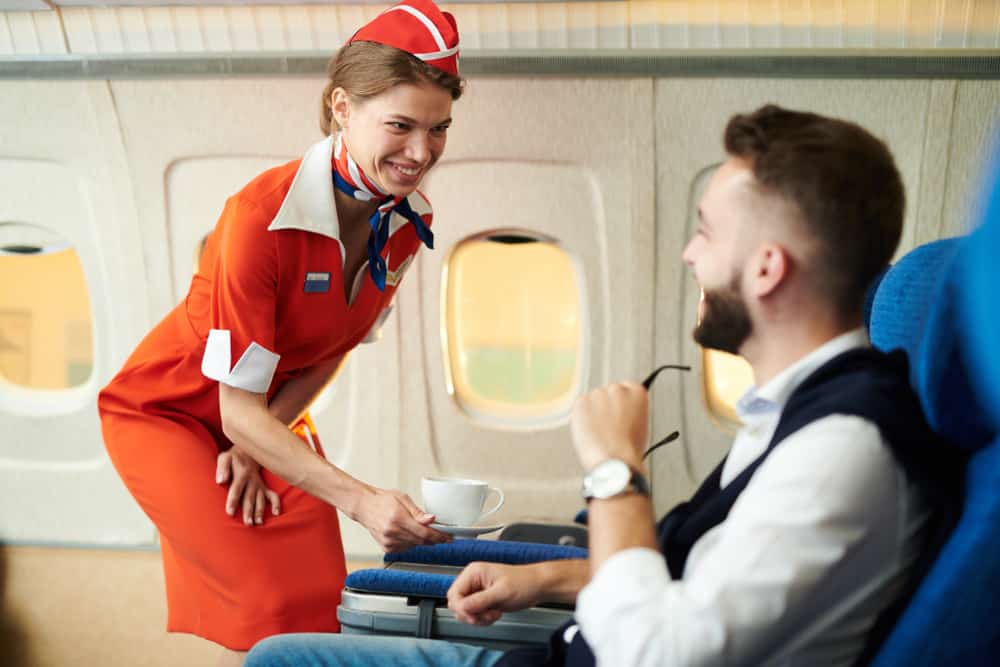 A flight attendant serving coffee to one of the passengers.