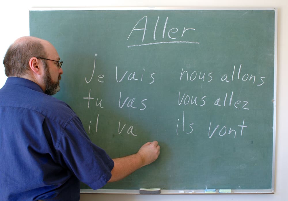 A French teacher writing some words on the chalkboard.