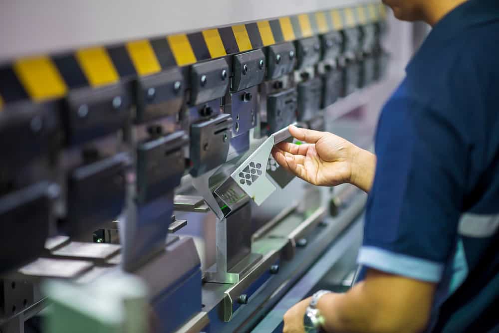 Technician operating a hydraulic bending machine.