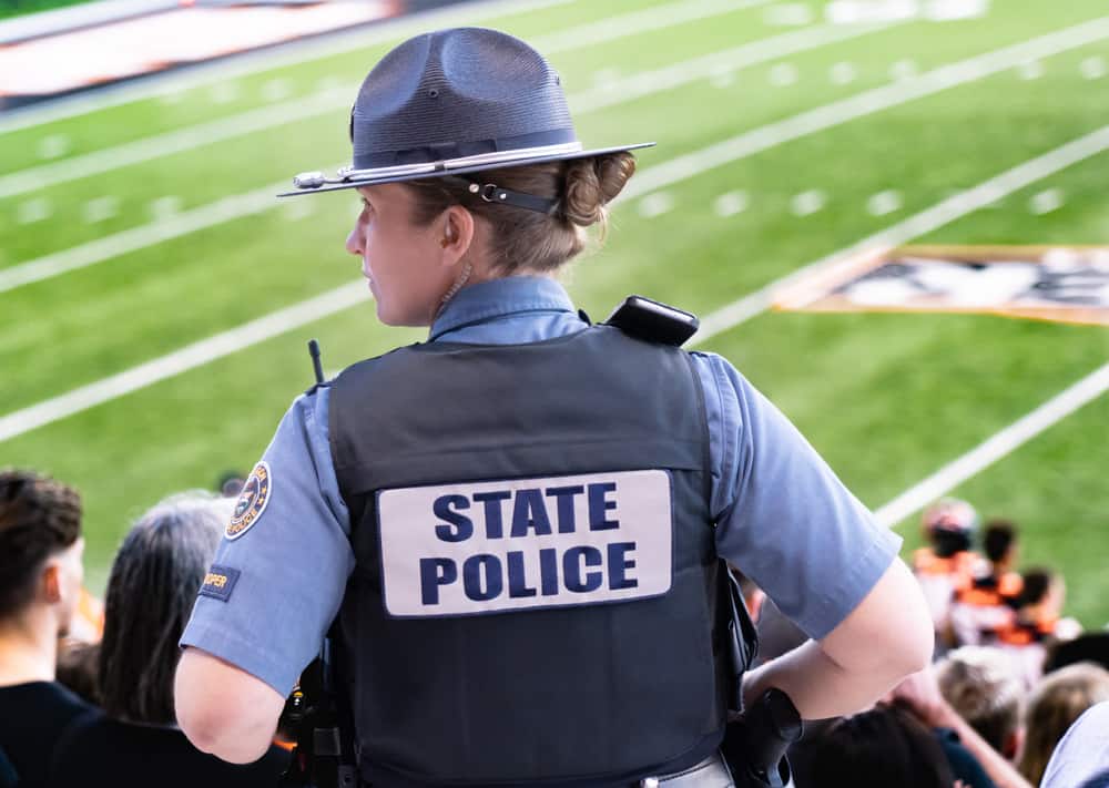 Back profile of state officer monitoring at a football game.