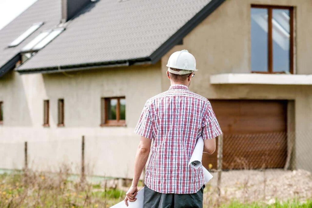 Back profile of an architect with a hard hat holding a roll of blueprints.