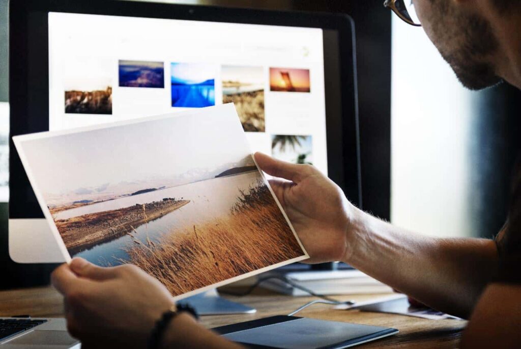 Art editor holding a printed photo of a landscape scene.