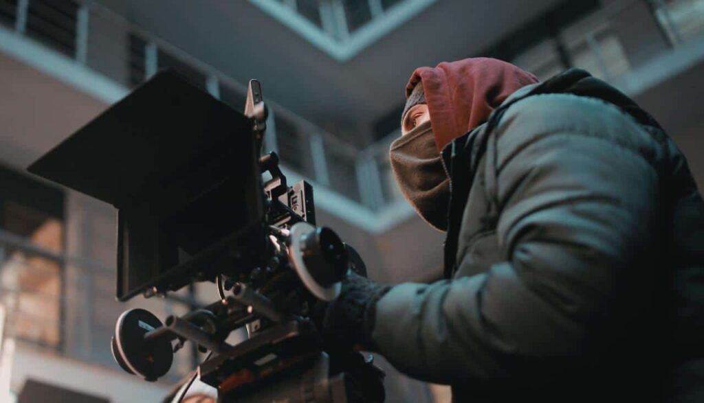 Cinematographer standing behind his camera.