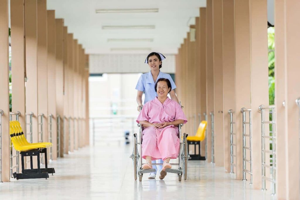 Geriatric nurse assisting her elderly patient on the wheelchair.