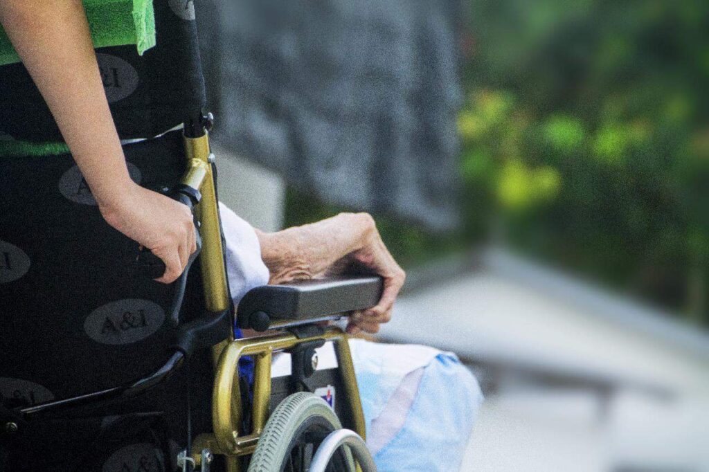 Hospice nurse assisting her patient on the wheelchair.