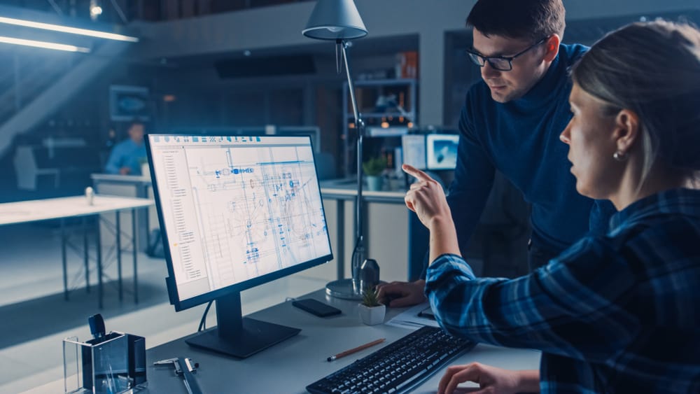 CAD technicians working on digital blueprints on computer.