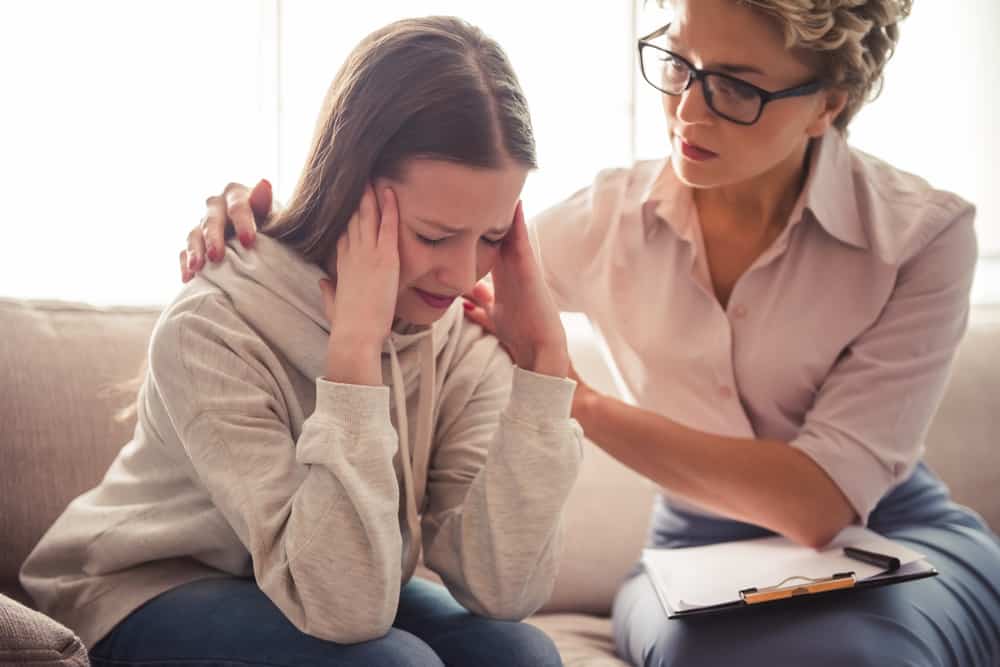 Child well-being specialist comforting the teenage girl.