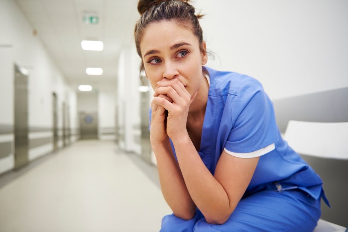 Worried and stressed nurse sitting on corridor.