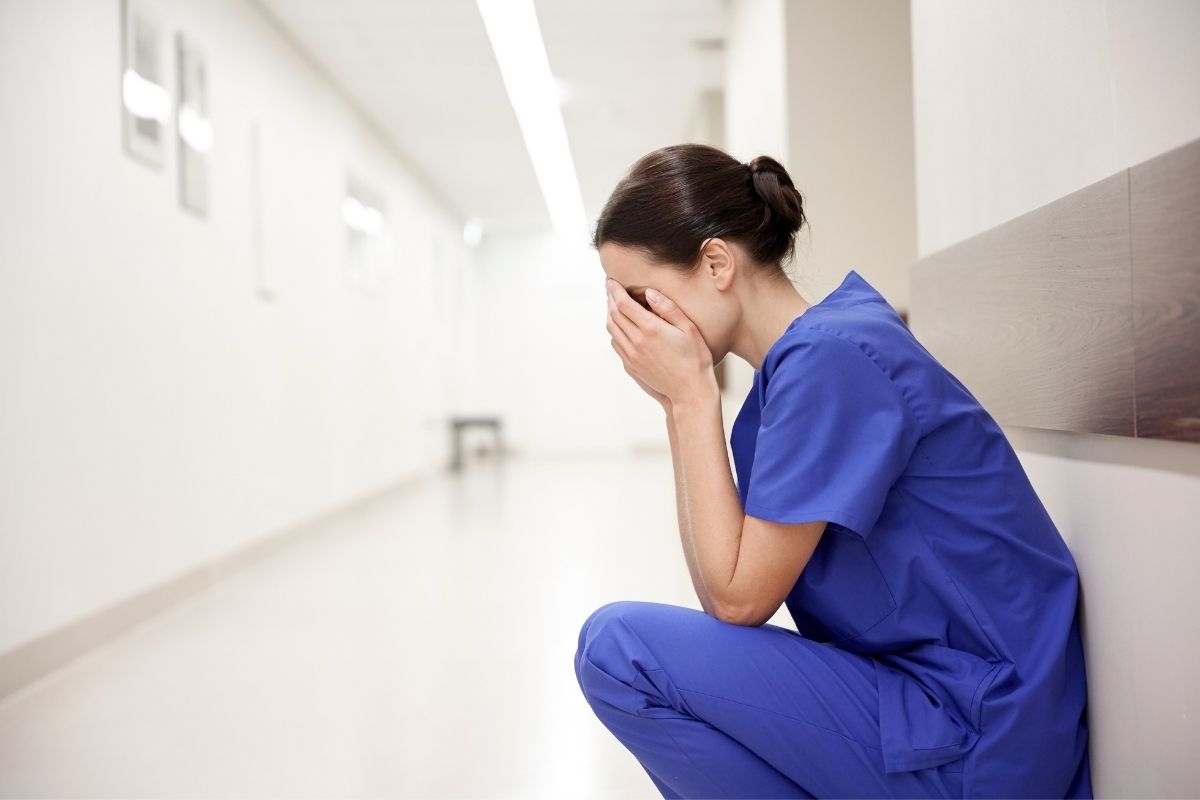 Sad and crying nurse on a hallway of the hospital.