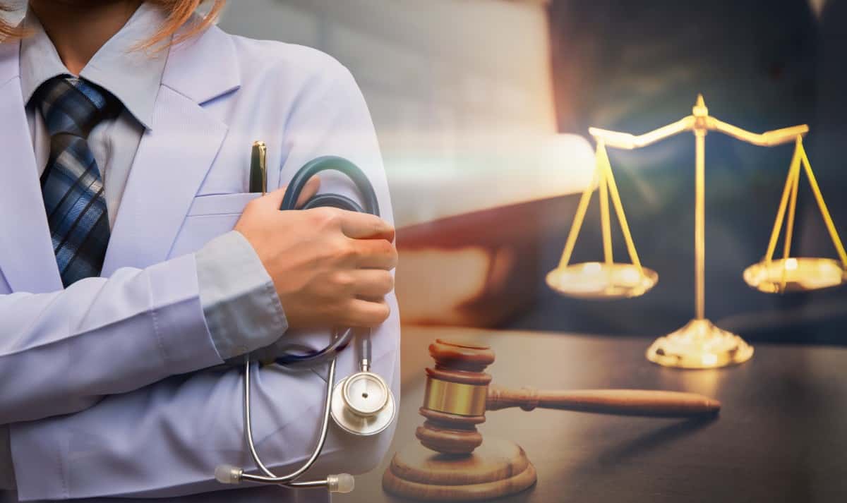 Nurse holding stethoscope with scale and gavel on the background.