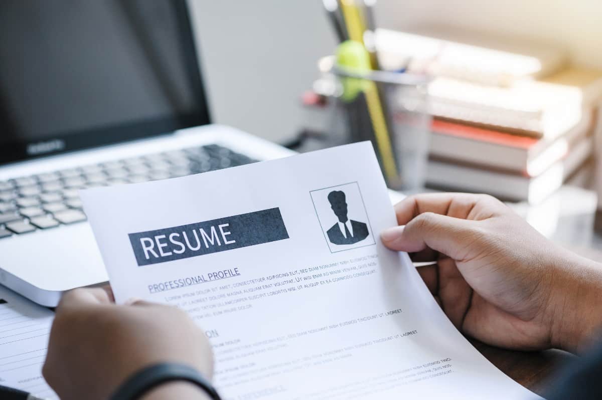 Man holding resume against laptop.