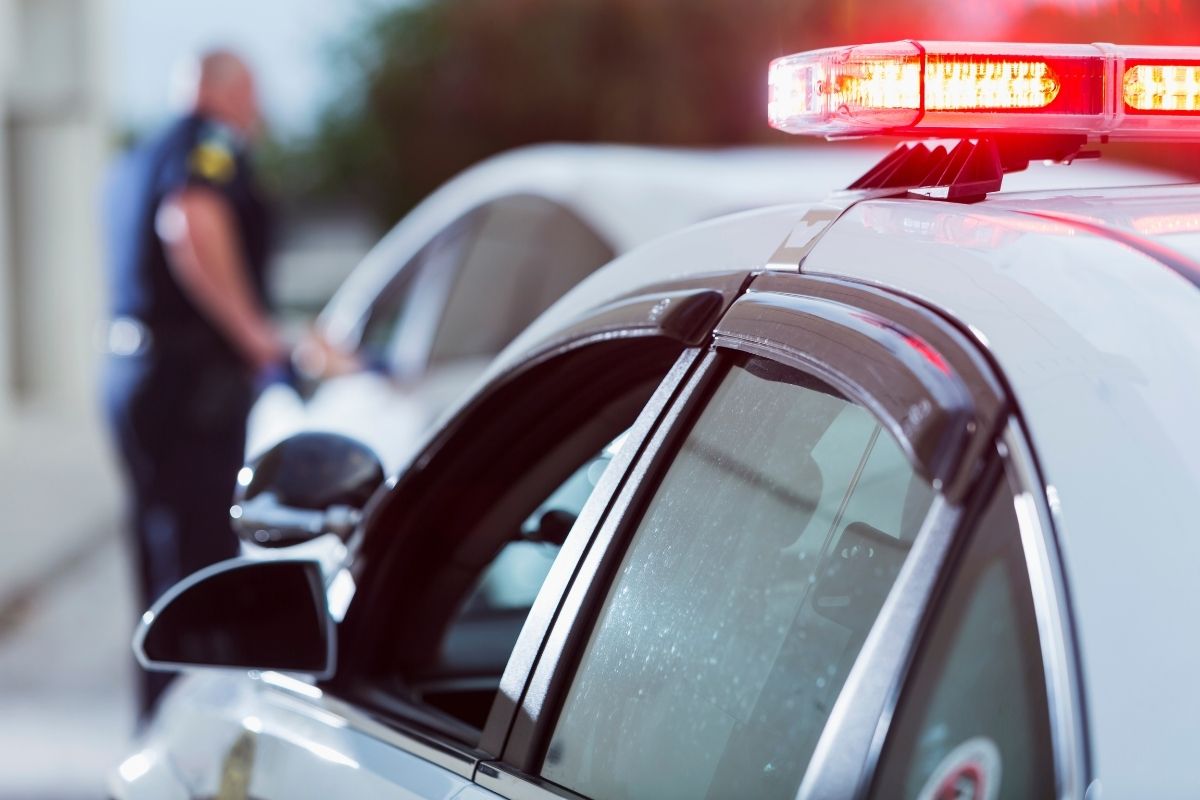 A police officer stands next to a car he pulled over for speeding.