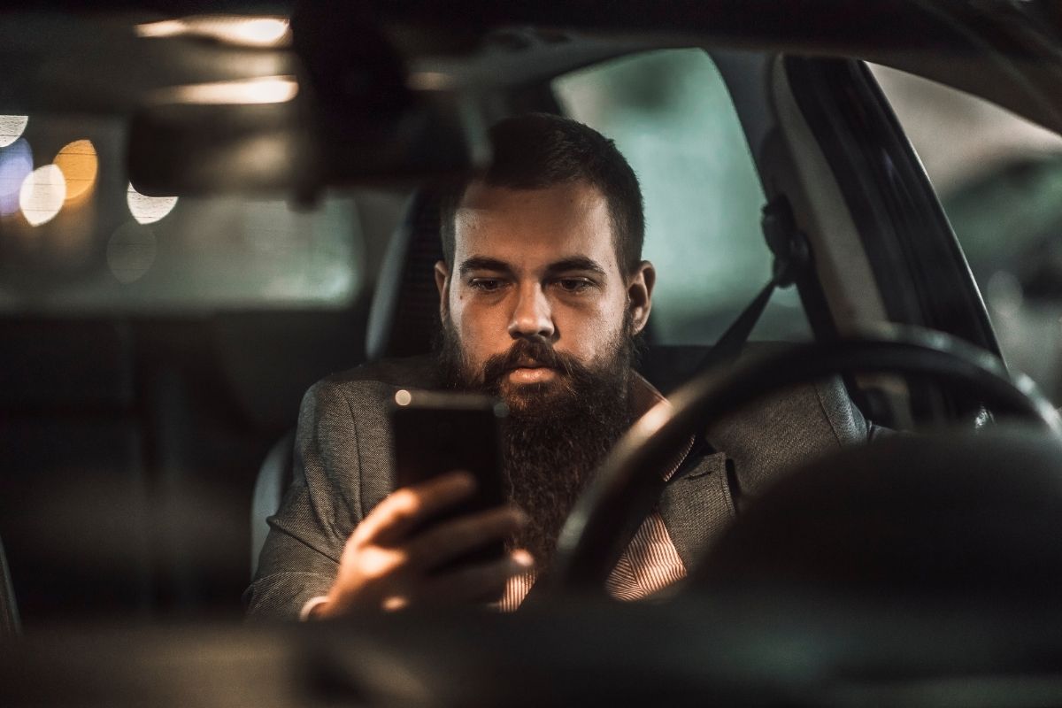 Young man driving while using his phone.