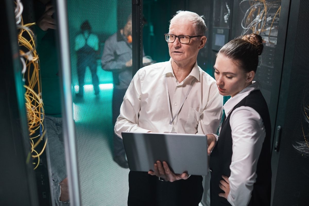 Data scientists using laptop in server room.