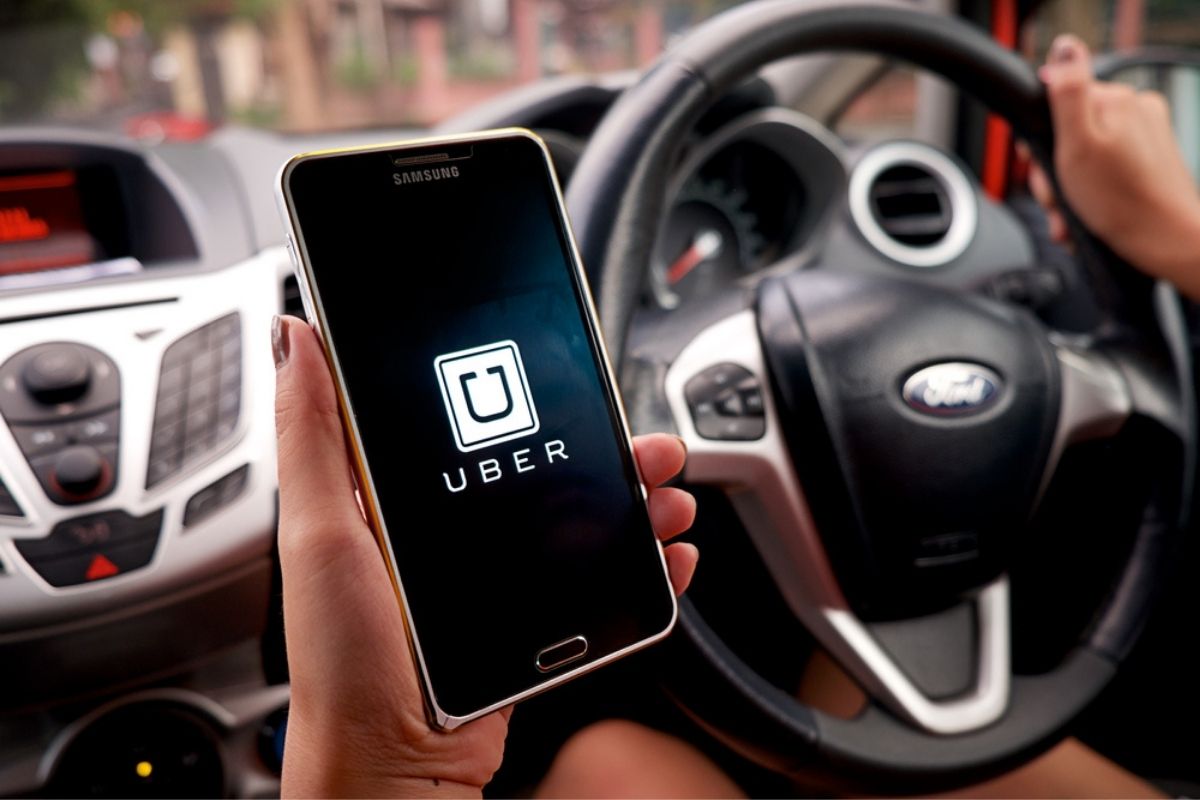 A woman hand holding Uber app showing on Samsung note 3 in the car.