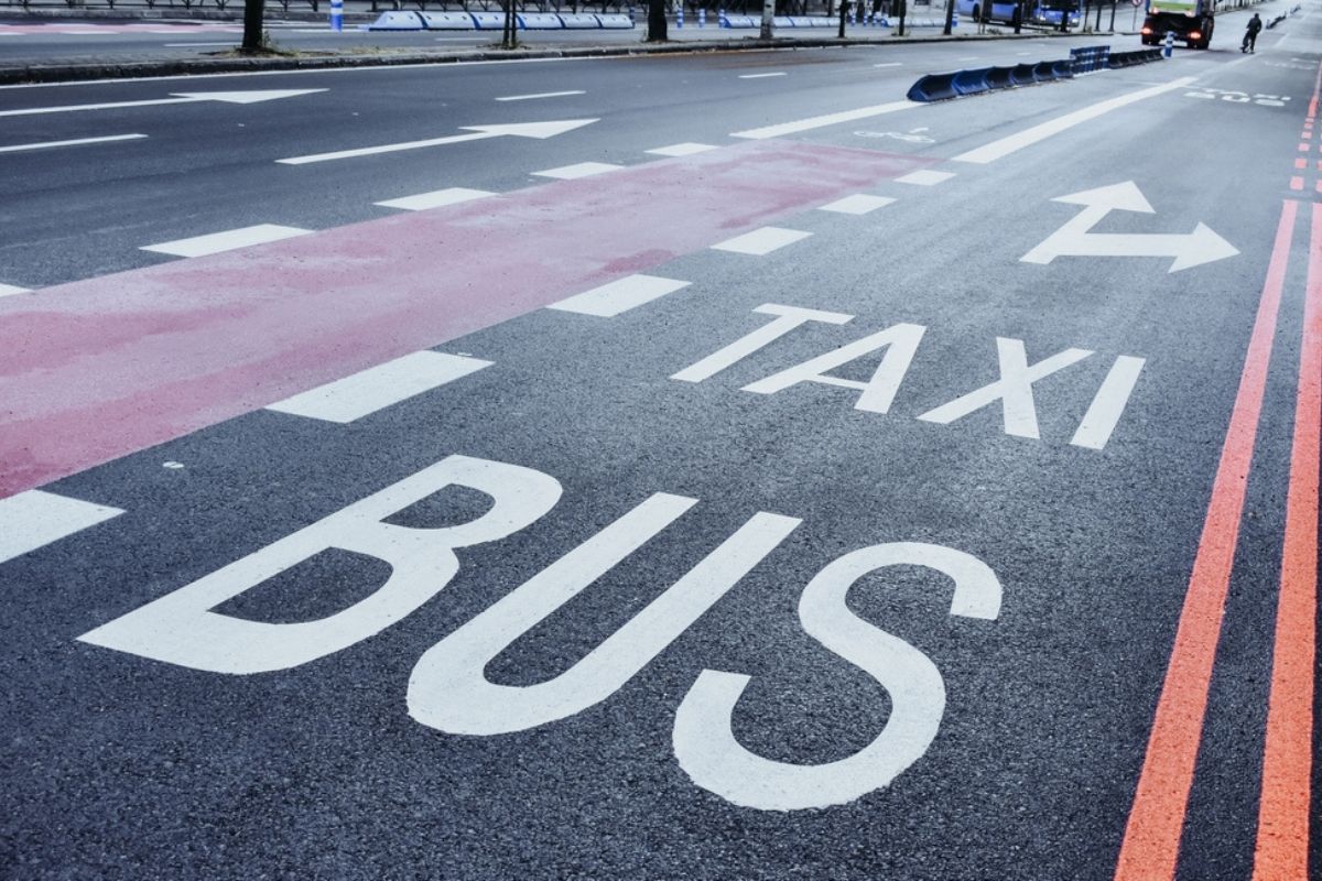 Horizontal reserved lane marking for different vehicles, buses, taxis, and bicycles on a deserted street.