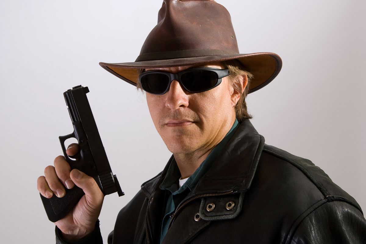 Bounty hunter holding a gun and wearing dark sunglasses.