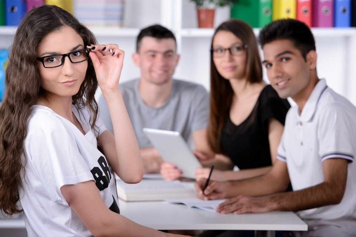 Group of young students while studying in classroom.