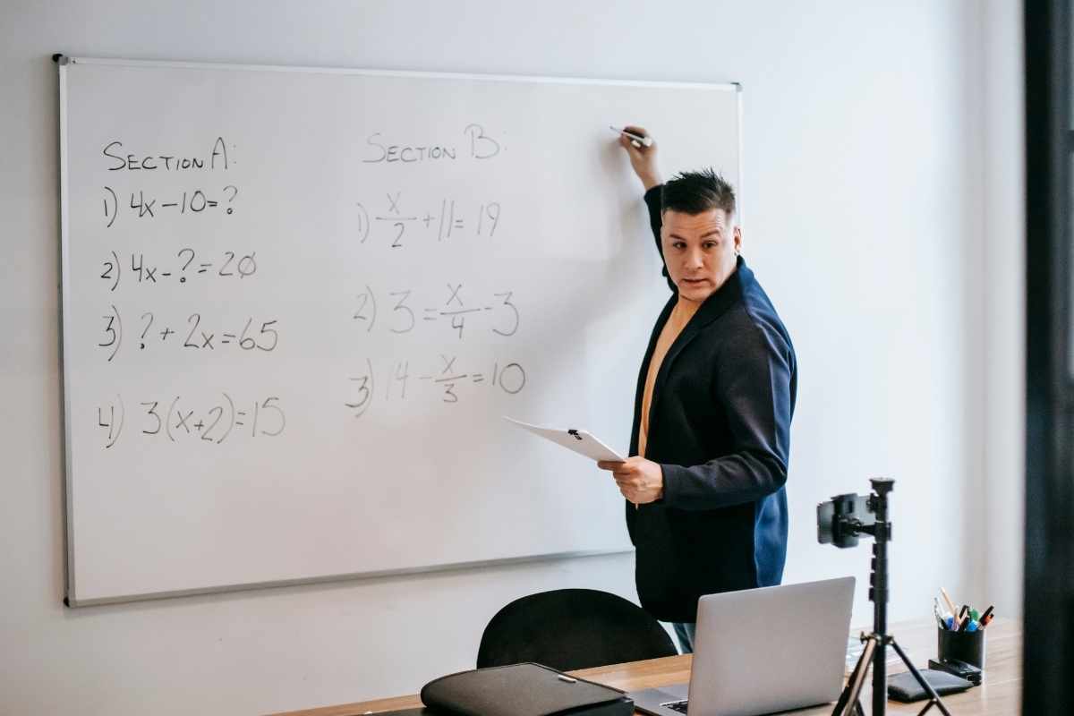 Photo of man teaching on white board.